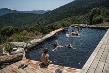 Des enfants se rafraichissent dans une piscine d'eau de source, face au massif du Caroux, Mons La Trivalle, 20 juillet 2024. 