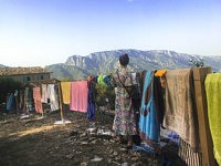 Une femme contemple la montagne du Caroux face à elle devant une palissade couvertes de serviettes de bain de toutes les couleurs, Toule, le 20 juillet 2024. 